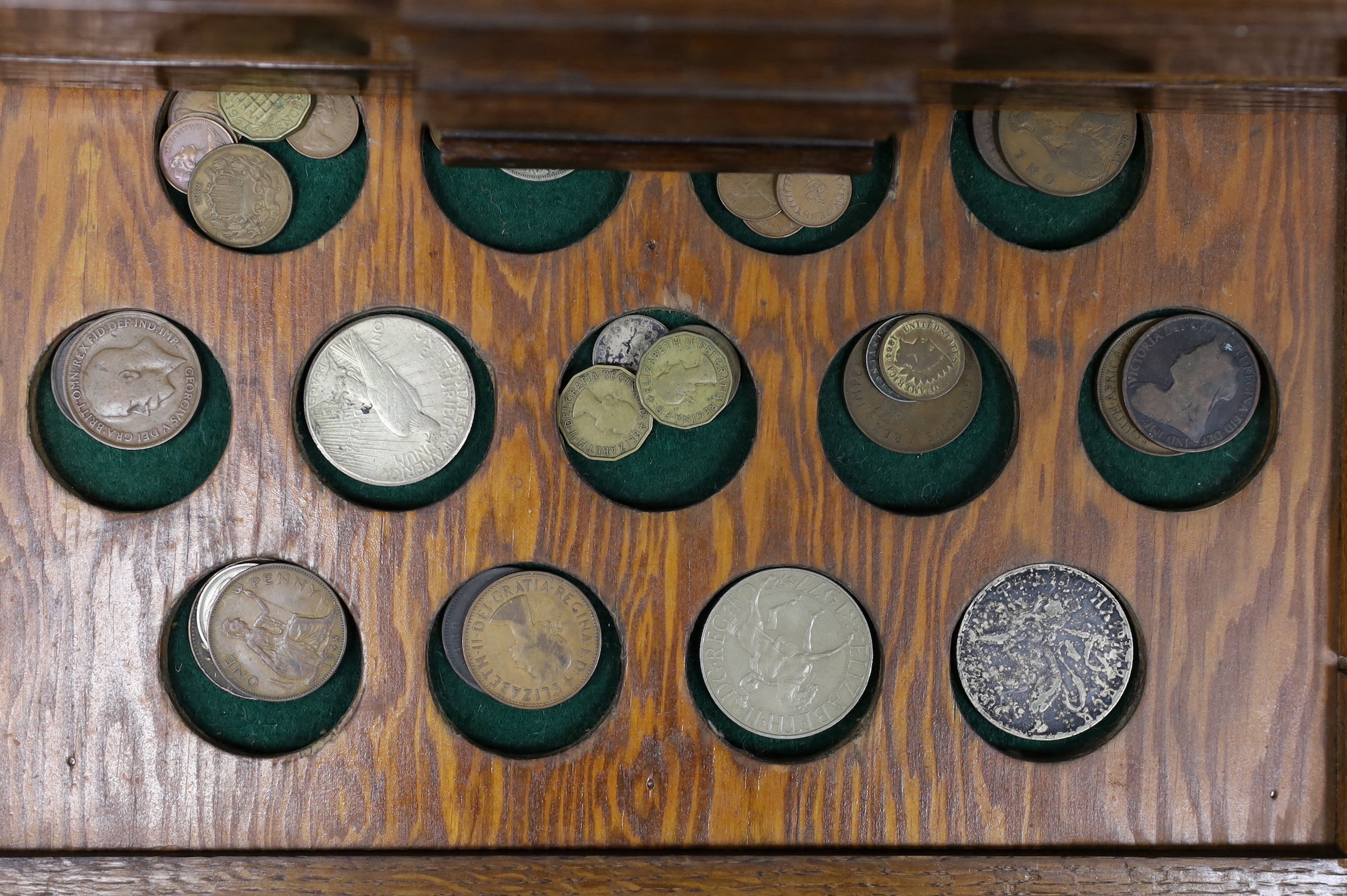 A collection of mixed coinage in a collectors cabinet, 27cm tall